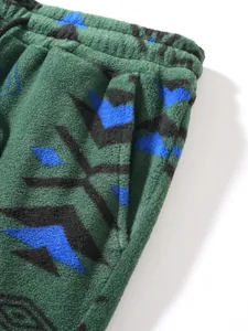 Close-up detail of men's green fleece pants featuring blue geometric patterns and pocket.