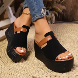 Vue détaillée de sandales à talons compensés noirs avec bride marron et plateforme.