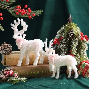 Zwei funkelnde weiße Weihnachts-Rentierfiguren auf Vintage-Büchern in festlicher Szene.
