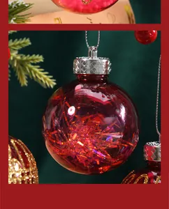 Detail of a red Christmas ball ornament filled with shimmering tinsel hanging on a tree