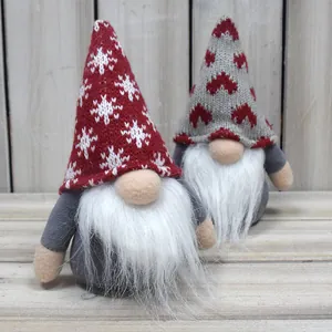 Detailed view of two handmade knitted Christmas gnomes with long white beards on wood