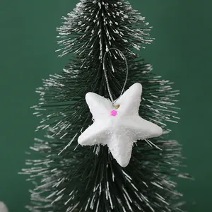 Close-up macro detail of white glitter foam star ornament hanging on a green tree