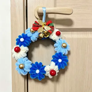 Ghirlanda natalizia fatta a mano con fiori blu e campanelli appesa a una porta