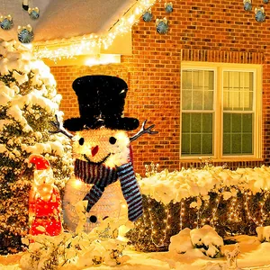 Festlicher beleuchteter weißer Schneemann mit schwarzem Hut in einer verschneiten Hofszene