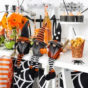 Detailansicht von drei Halloween-Gnomen mit langen Beinen und Besen auf festlichem Tisch