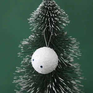 Detailed view of a white sparkling foam ball Christmas ornament on a green tree branch.