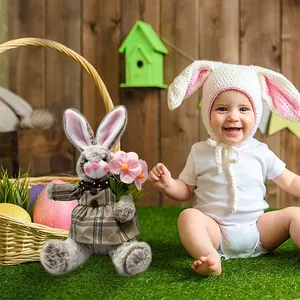 Detailed view of plush Easter bunny toy in plaid dress sitting on grass next to a happy baby