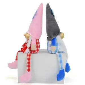 Pair of cute long-legged gnomes with resin faces sitting back-to-back on a white box.