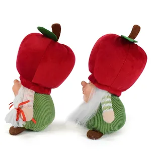 Detail of cute Christmas plush gnomes with red apple hats and green corduroy bodies.