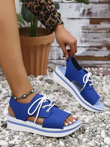 Stylish women's blue platform peep-toe sandals with white lace-up detail in a casual setting.