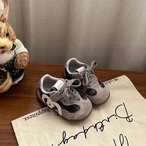 Detailed close-up of grey suede toddler sneakers with plaid pattern and soft gum sole.