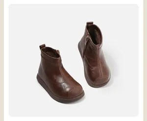 Detalle de botines de cuero marrón para niños pequeños con cremallera lateral.