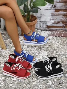 Collection of colorful platform peep-toe lace-up sandals on pebbled beach background
