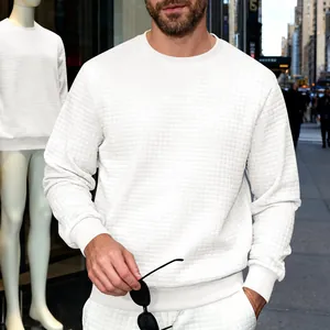 Close-up detail of white sweatshirt featuring unique square waffle texture and ribbed cuffs