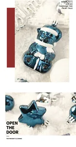 Detailaufnahme von blauem Bär und sternförmigem Christbaumschmuck auf weißem Schneehintergrund