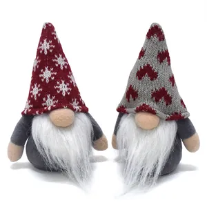 Macro view of two knitted Christmas gnomes with snowflake and heart patterns on their hats.