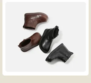 Vista detallada de botines de cuero para bebés en negro y marrón con cremallera lateral.