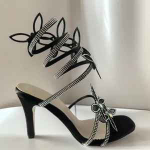 Detail der schwarzen Strass-Schmetterlings-Stiletto-Sandalen mit quadratischer Zehe.