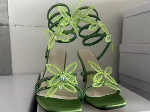 Detailansicht der grünen Satin-Sandalen mit Strass-Schmetterling und Wickelriemen