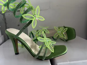Detailansicht der lindgrünen Sandalen mit Strass-Schmetterlingen und Schnürung am Knöchel.