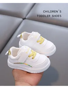 Dettaglio ravvicinato di scarpe primi passi in pelle bianca con lacci gialli e velcro