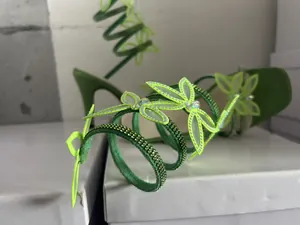 Detailaufnahme grüner Wickelsandalen mit glitzernden Strassschmetterlingen und Stilettoabsatz