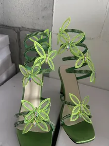 Detail grüner Wickelsandalen mit Strass-Schmetterlingsdekor und eckiger Zehenpartie.