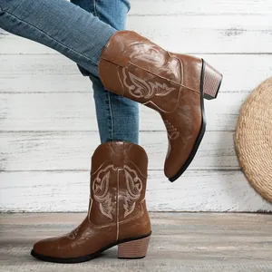 Detailed side view of brown Western cowboy boots with intricate white embroidery and block heel.