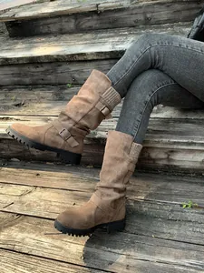 Lifestyle-weergave van bruine halflange slouchy laarzen met gespen en gebreide kraag
