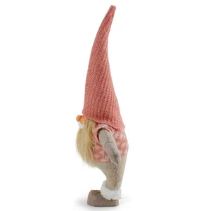 Side profile of a pink knit Christmas gnome figurine with tall hat on white background