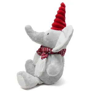 Profile view of a cute grey plush elephant wearing a red pointed hat and a striped scarf.