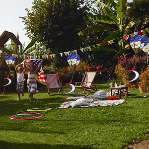 Moulins à vent patriotiques en montgolfière suspendus dans un jardin ensoleillé.