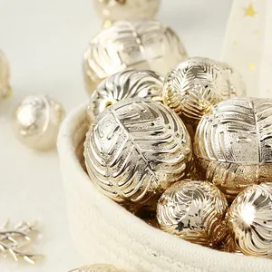 Palline di Natale color oro champagne con motivi a foglia in un cesto intrecciato bianco