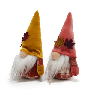 Close-up view of two decorative autumn harvest gnomes with velvet hats and maple leaves