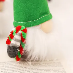 Décoration de Noël gnome mignon avec chapeau en feutre vert et barbe blanche sur un livre.
