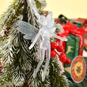 Detailansicht eines glitzernden Feen-Anhängers an einem verschneiten Weihnachtsbaum.