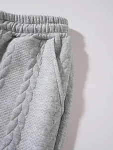 Dettaglio macro di pantaloni sportivi grigi trapuntati a trecce con vita elasticizzata