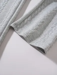 Dettaglio macro della trama in maglia jacquard strutturata di un maglione grigio da uomo.