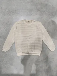Detailed view showing the textured small square jacquard pattern of this beige crew neck sweatshirt