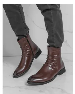 Détail de bottines Chelsea en cuir marron à bout pointu avec fermeture éclair et plis.