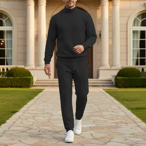 Dettaglio del completo da uomo con maglione a collo alto nero a trecce e pantaloni jogger.