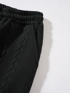 Macro detail of black cable-knit warm trousers featuring elastic waistband and side pocket