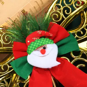 Close-up detail of festive Santa Claus head with green hat on a plush red and green bow.