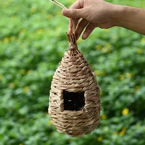 Handcrafted natural grass woven bird nest with a hanging rope for outdoor garden use