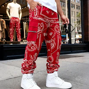 Low angle view of red paisley cargo pants featuring a side utility pocket with silver zipper