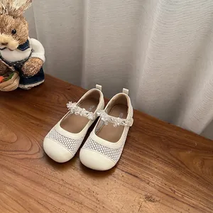 Dettaglio delle scarpe Mary Jane crema da bambina con rete e fiori di cristallo