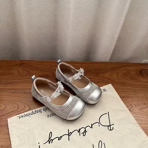 Primo piano di scarpe in rete argentata per bambine con cinturini in cristallo