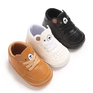 Vue détaillée de baskets pour bébé en marron, blanc et noir avec un motif d'ours mignon.