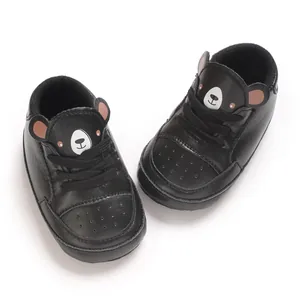 Vue détaillée de baskets noires pour bébé avec un joli motif de visage d'ours en peluche.