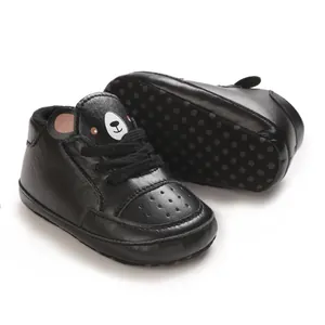 Vue détaillée de baskets noires pour bébé garçon avec un motif d'ours mignon.